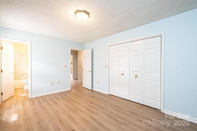 unfurnished bedroom with light wood-style floors, a textured ceiling, baseboards, and a closet