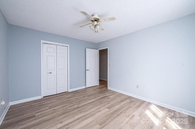 unfurnished bedroom featuring a textured ceiling, wood finished floors, a ceiling fan, baseboards, and a closet