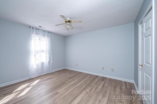 empty room featuring a ceiling fan, a textured ceiling, baseboards, and wood finished floors