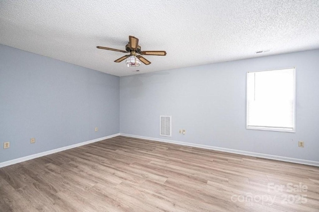 unfurnished room featuring ceiling fan, a textured ceiling, visible vents, baseboards, and light wood-style floors