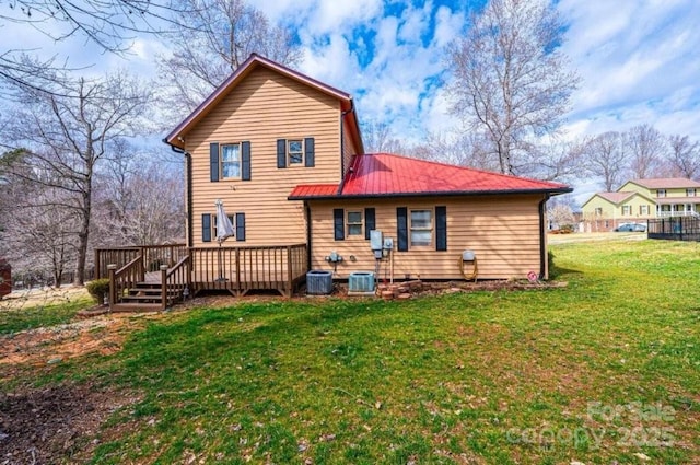 back of property featuring metal roof, a lawn, a wooden deck, and central air condition unit