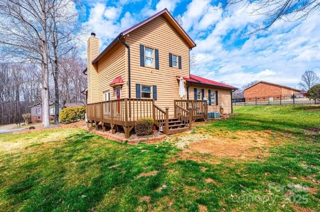 rear view of house with central AC unit, fence, a lawn, a wooden deck, and a chimney