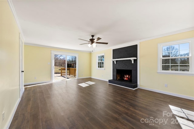 unfurnished living room featuring ornamental molding, a brick fireplace, wood finished floors, and baseboards