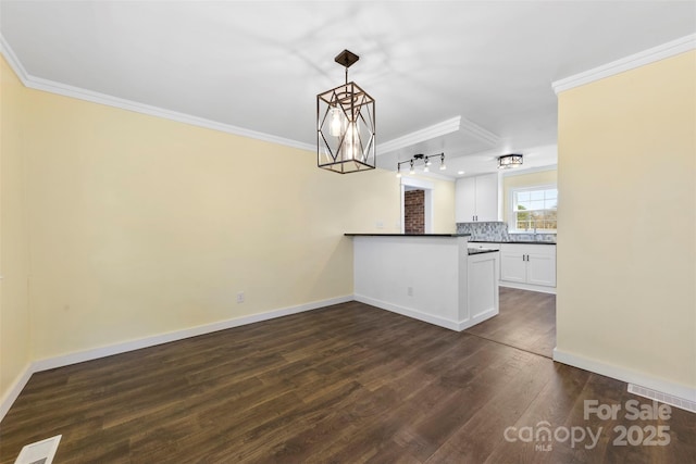 kitchen featuring baseboards, white cabinets, decorative backsplash, dark wood-type flooring, and crown molding