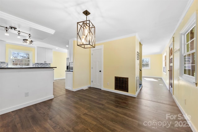 interior space with dark wood finished floors, visible vents, an inviting chandelier, ornamental molding, and baseboards