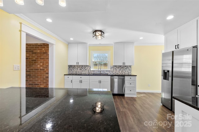 kitchen with appliances with stainless steel finishes, crown molding, a sink, and decorative backsplash