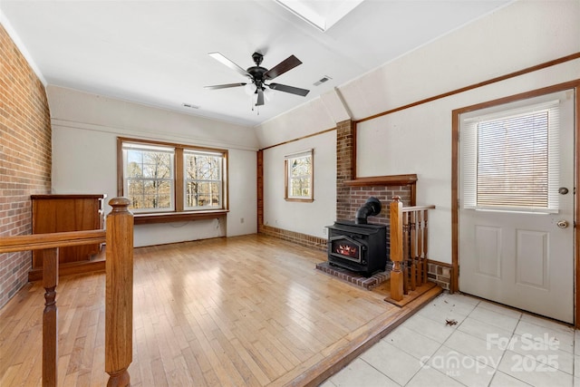 living room with visible vents, brick wall, light wood finished floors, and a ceiling fan