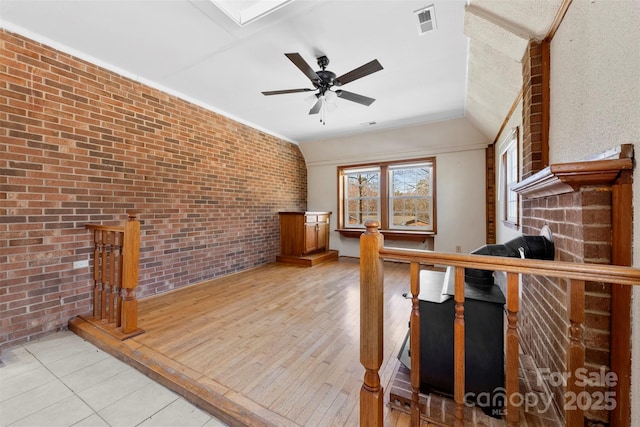 interior space featuring visible vents, ceiling fan, light wood-style flooring, and brick wall