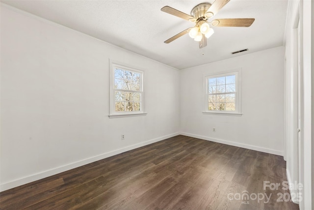 unfurnished room featuring a healthy amount of sunlight, visible vents, baseboards, and dark wood-style flooring