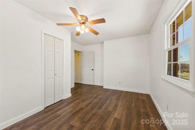 unfurnished bedroom featuring a closet, dark wood finished floors, and baseboards