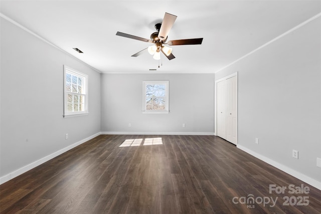 unfurnished room with dark wood-style flooring, a wealth of natural light, and baseboards