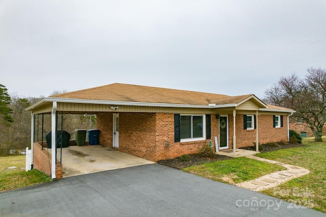 ranch-style home featuring a carport, driveway, a front yard, and brick siding