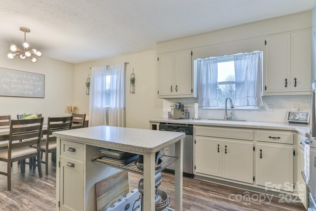 kitchen with a healthy amount of sunlight, dark wood-style floors, a sink, decorative backsplash, and stainless steel dishwasher