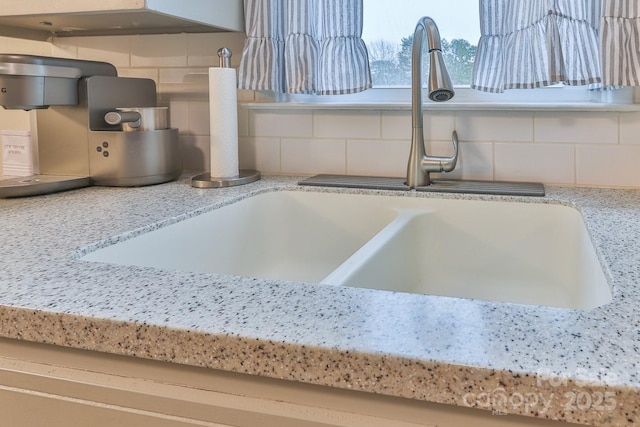 room details with a sink, light stone countertops, and tasteful backsplash