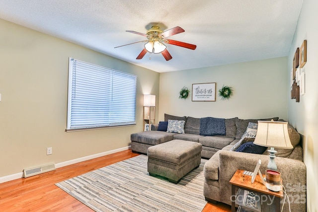 living room with visible vents, a ceiling fan, a textured ceiling, wood finished floors, and baseboards