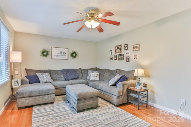 living area featuring plenty of natural light, baseboards, ceiling fan, and wood finished floors