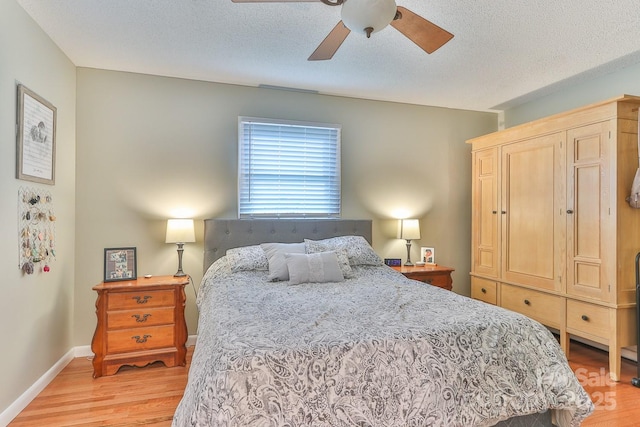 bedroom with light wood-type flooring, baseboards, a textured ceiling, and a ceiling fan