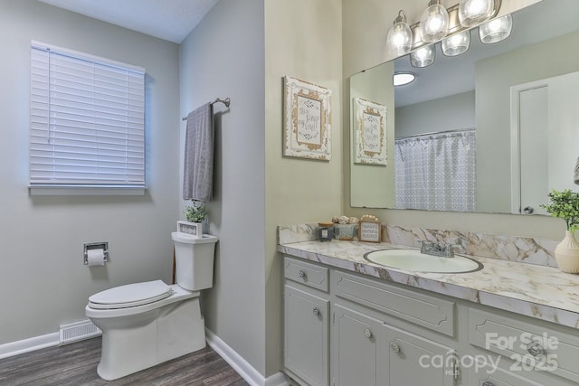 bathroom featuring visible vents, toilet, wood finished floors, baseboards, and vanity