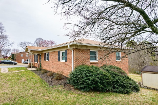 view of side of home with a yard and brick siding