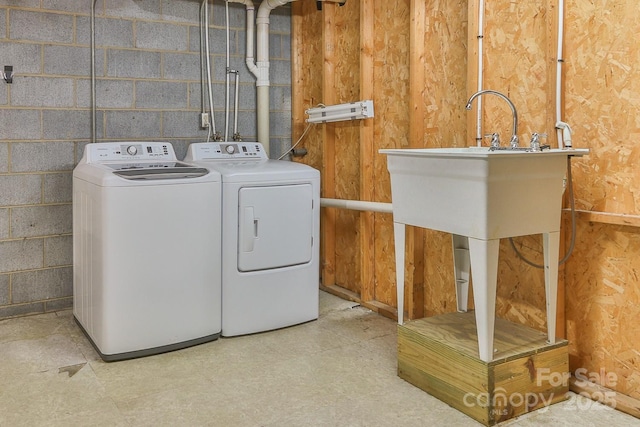 washroom featuring laundry area, concrete block wall, and washing machine and dryer