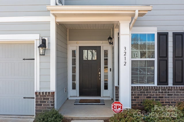 doorway to property featuring a garage and brick siding