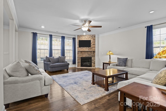 living room featuring a stone fireplace, recessed lighting, dark wood-style flooring, a ceiling fan, and crown molding