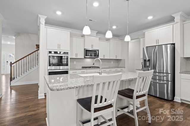 kitchen featuring dark wood-style flooring, stainless steel appliances, tasteful backsplash, visible vents, and ornamental molding