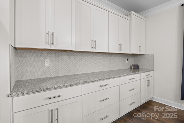 kitchen with dark wood finished floors, backsplash, ornamental molding, white cabinetry, and light stone countertops