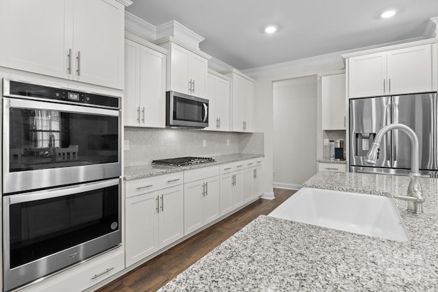 kitchen featuring a sink, appliances with stainless steel finishes, dark wood-style floors, tasteful backsplash, and crown molding