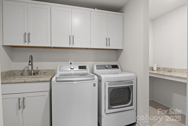 laundry area with cabinet space, washing machine and dryer, and a sink