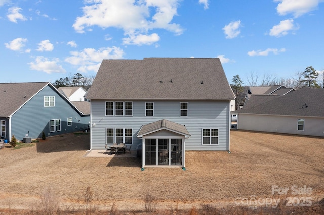 rear view of house featuring central AC, a shingled roof, a patio area, and a sunroom