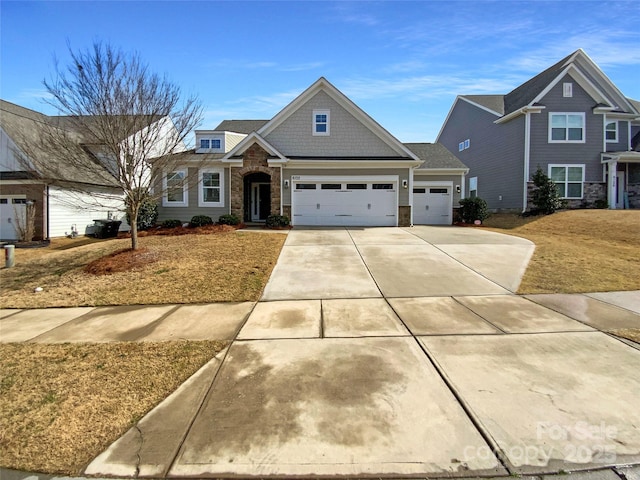 view of front of house with a garage, stone siding, and driveway