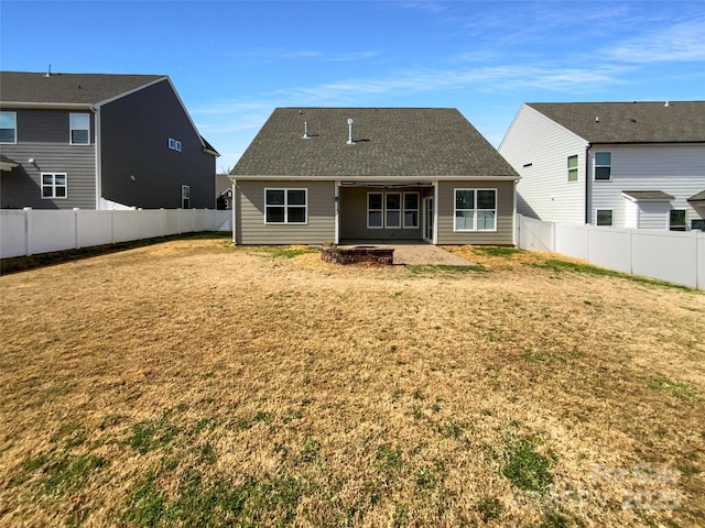 back of house with a yard, a shingled roof, and a fenced backyard