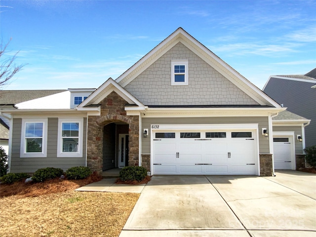 craftsman-style house featuring a garage, concrete driveway, and stone siding