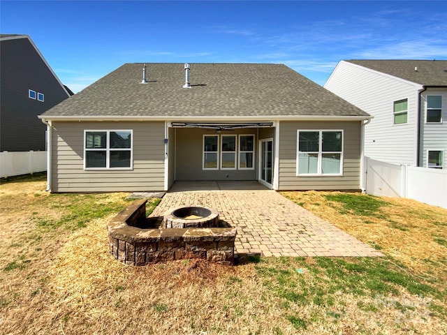 back of property with a patio, a fenced backyard, a fire pit, a yard, and roof with shingles