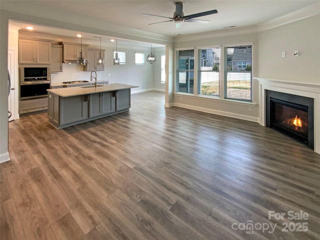 kitchen with a glass covered fireplace, open floor plan, oven, built in microwave, and gray cabinetry