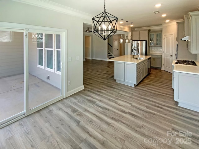 kitchen featuring ornamental molding, light wood-type flooring, light countertops, and under cabinet range hood