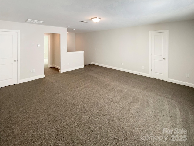 spare room featuring dark colored carpet, visible vents, and baseboards