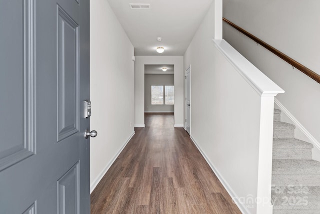 hall with stairway, wood finished floors, visible vents, and baseboards