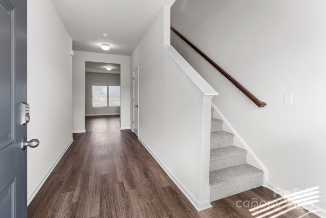 hallway with dark wood-style floors, stairs, and baseboards