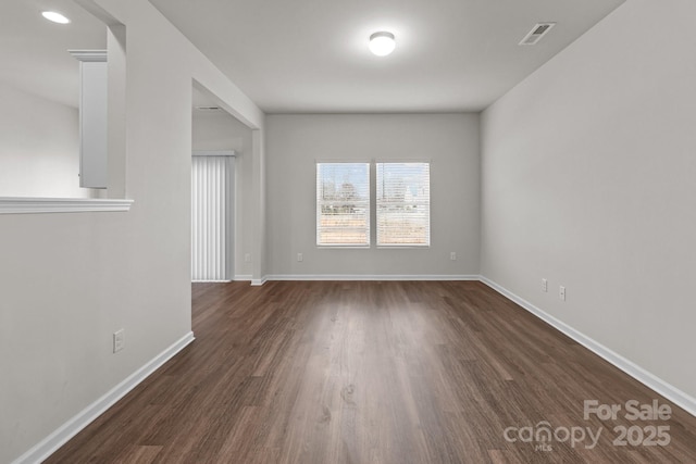 spare room featuring visible vents, dark wood finished floors, and baseboards