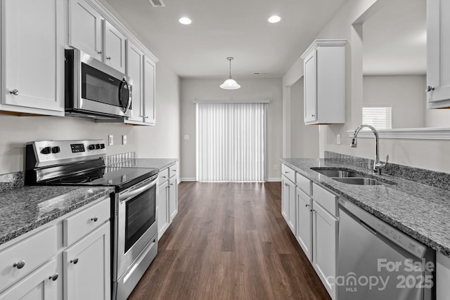 kitchen featuring stainless steel appliances, stone countertops, white cabinetry, and a sink