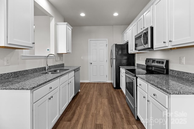 kitchen with stainless steel appliances, a sink, white cabinetry, dark wood-style floors, and dark stone countertops