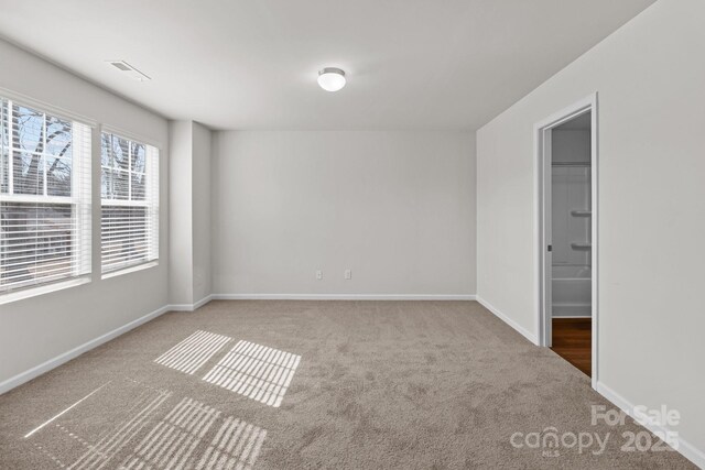 empty room featuring carpet floors, visible vents, and baseboards