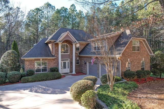 view of front facade featuring a shingled roof, concrete driveway, brick siding, and a garage