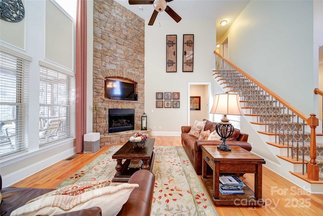 living room with ceiling fan, stairs, wood finished floors, and a towering ceiling