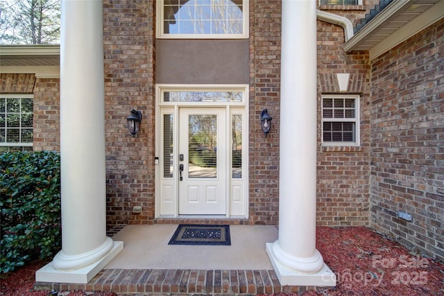 doorway to property with brick siding and covered porch