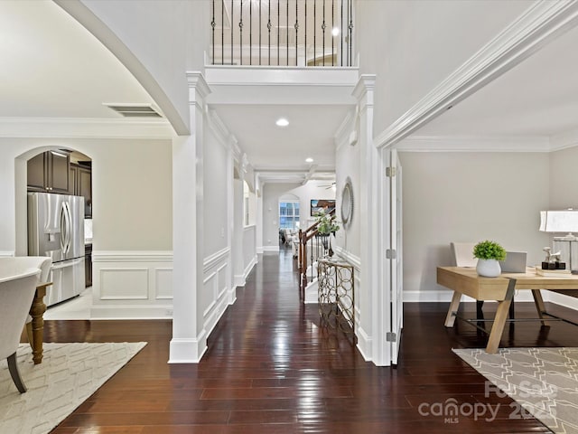 foyer featuring hardwood / wood-style floors, a decorative wall, visible vents, and ornamental molding