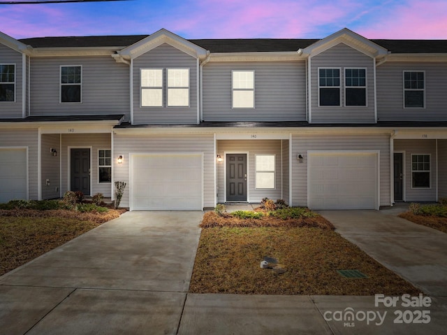 multi unit property featuring an attached garage and concrete driveway