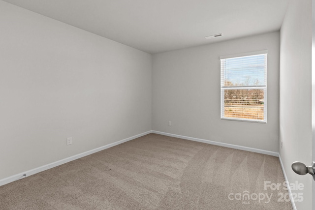 unfurnished room with carpet, visible vents, and baseboards